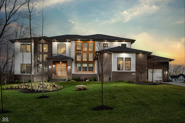 prairie-style house featuring brick siding, a garage, a front yard, french doors, and driveway