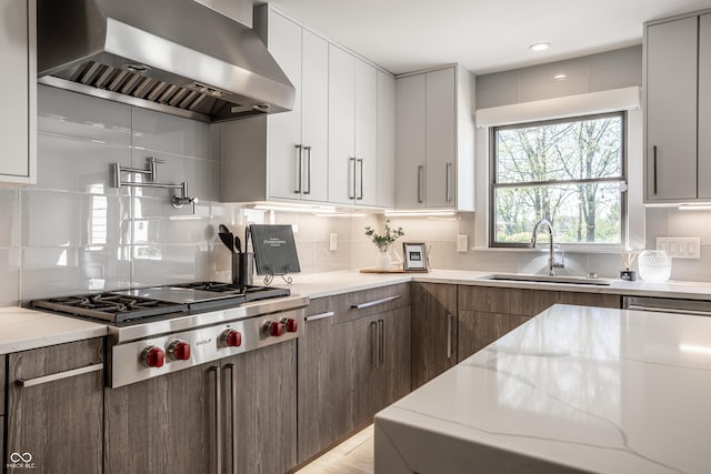 1995 W 116th St, Carmel, IN 46032 - kitchen with tasteful backsplash, stainless steel gas cooktop, light stone countertops, a sink, and wall chimney exhaust hood