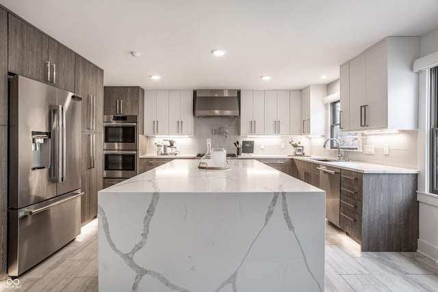 1995 W 116th St, Carmel, IN 46032 - kitchen featuring wall chimney range hood, a sink, stainless steel appliances, a kitchen island, and modern cabinets