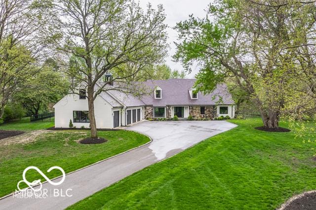 1995 W 116th St, Carmel, IN 46032 - cape cod-style house with a garage, a front lawn, driveway, and stone siding