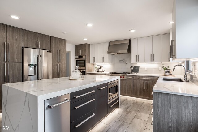 1995 W 116th St, Carmel, IN 46032 - kitchen featuring a kitchen island, modern cabinets, wall chimney range hood, a sink, and stainless steel appliances