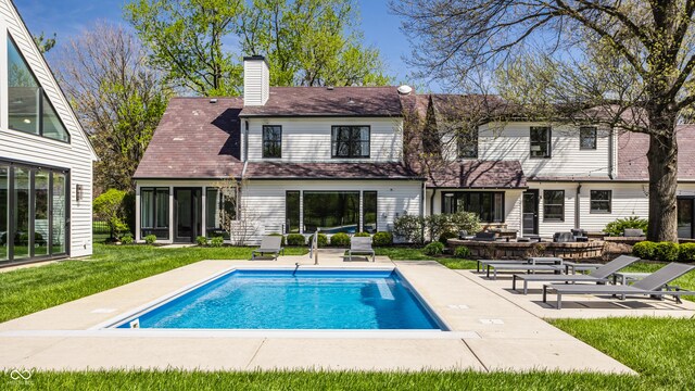 1995 W 116th St, Carmel, IN 46032 - back of property featuring a lawn, a chimney, a patio area, and an outdoor pool