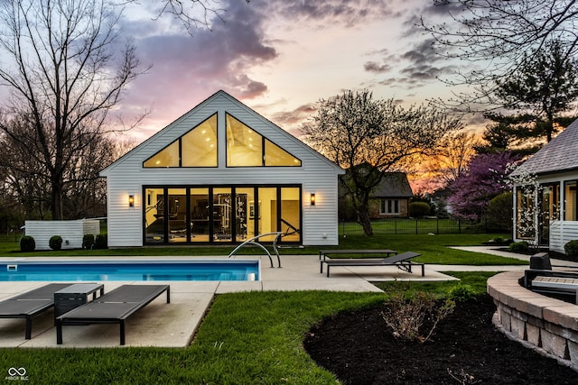 1995 W 116th St, Carmel, IN 46032 - back of house at dusk with an outdoor structure, an exterior structure, an outdoor pool, and a patio