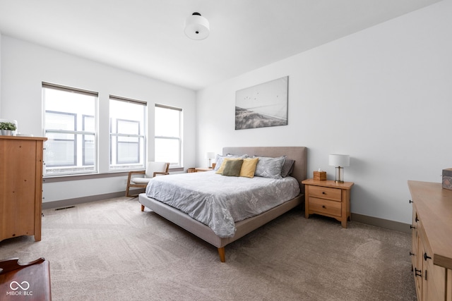 bedroom featuring baseboards, light colored carpet, and visible vents