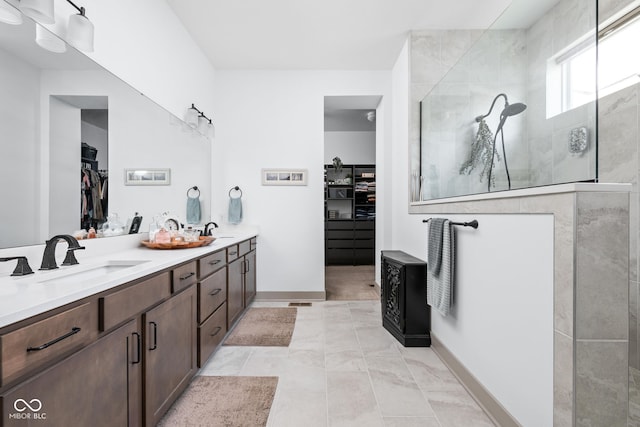 bathroom featuring double vanity, a sink, walk in shower, and a spacious closet