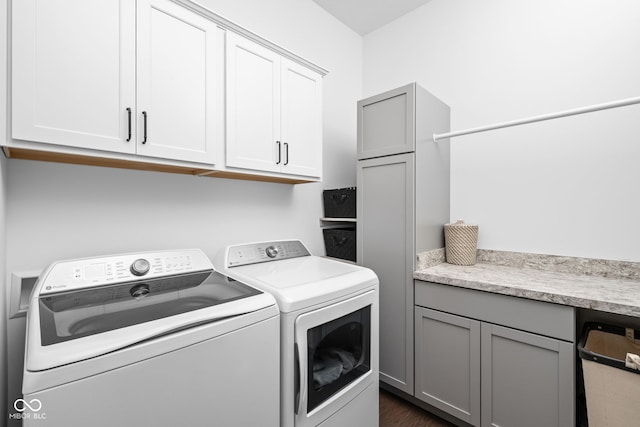 clothes washing area featuring dark wood-style floors, cabinet space, and washer and dryer