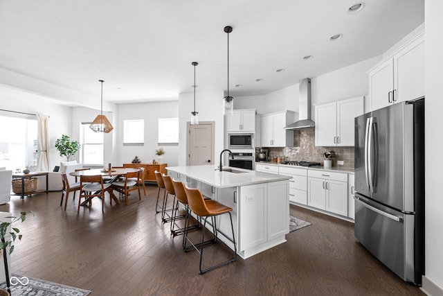 kitchen featuring light countertops, tasteful backsplash, wall chimney range hood, and stainless steel appliances