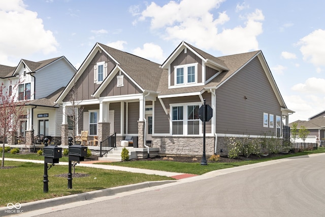 craftsman house with a shingled roof, a front lawn, stone siding, board and batten siding, and a porch