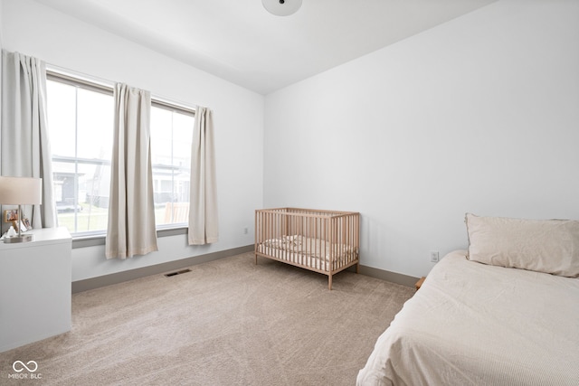 carpeted bedroom featuring visible vents, baseboards, and multiple windows
