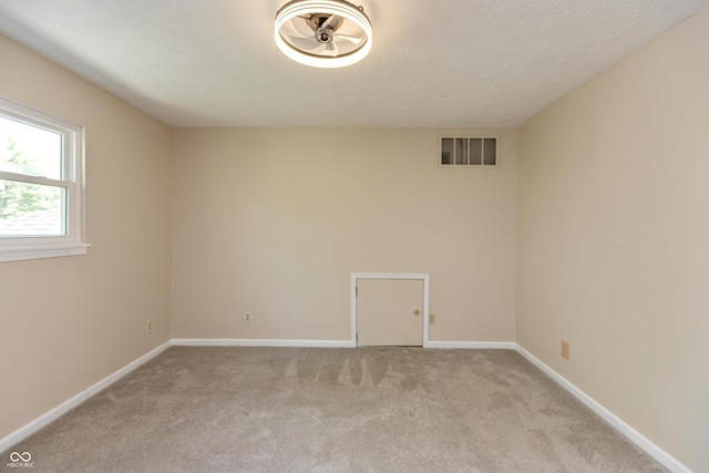 unfurnished room with a textured ceiling, light carpet, and baseboards