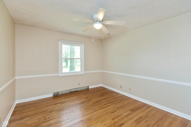 empty room with light wood finished floors, a ceiling fan, baseboard heating, and a textured ceiling