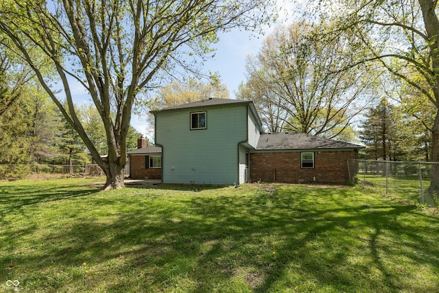 back of property featuring fence and a lawn