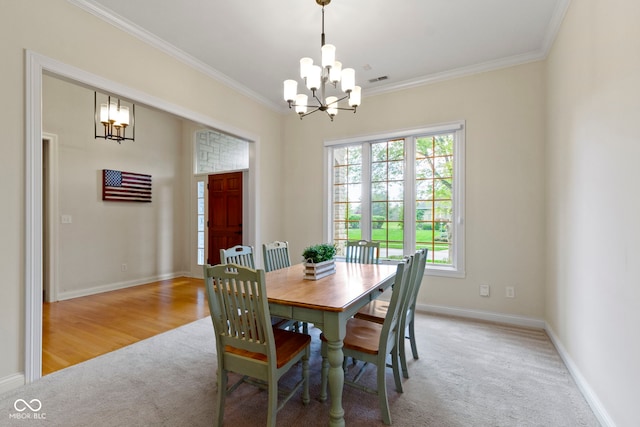 dining space with an inviting chandelier, baseboards, ornamental molding, and light colored carpet