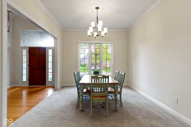 carpeted dining space featuring crown molding, baseboards, and a chandelier