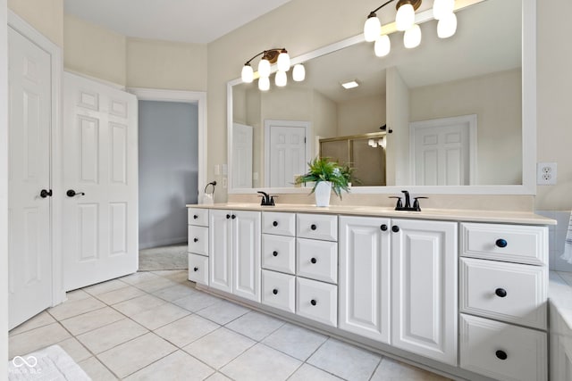 full bath featuring double vanity, tile patterned floors, a stall shower, and a sink