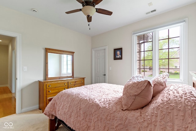 bedroom with light colored carpet, baseboards, visible vents, and a ceiling fan