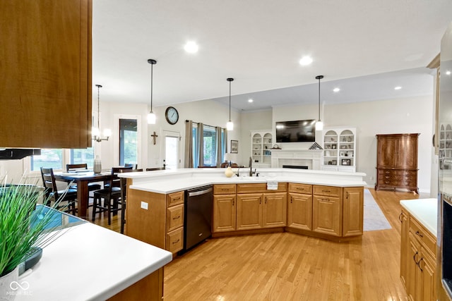 kitchen featuring light countertops, dishwashing machine, light wood finished floors, and a fireplace