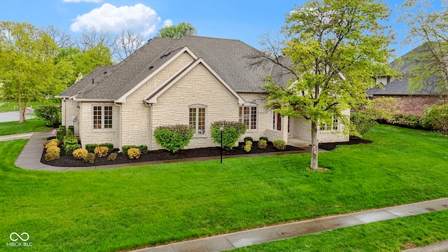 ranch-style house featuring a shingled roof, stone siding, and a front lawn