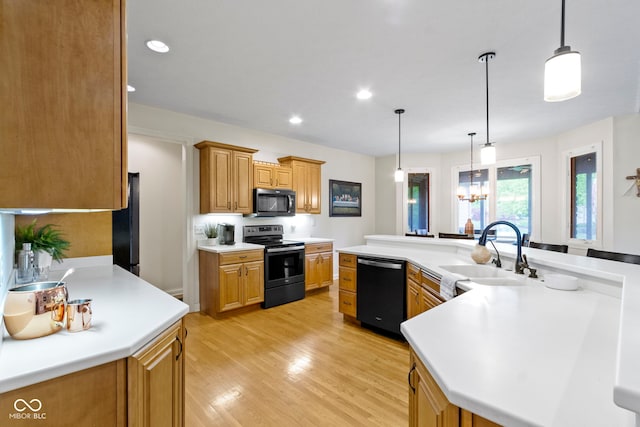 kitchen featuring a sink, light countertops, recessed lighting, light wood-type flooring, and black appliances