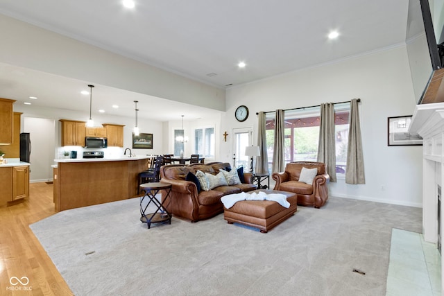 living area featuring recessed lighting, a fireplace with flush hearth, light wood-style flooring, and ornamental molding
