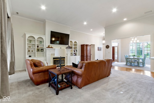carpeted living room with crown molding, recessed lighting, a glass covered fireplace, and an inviting chandelier