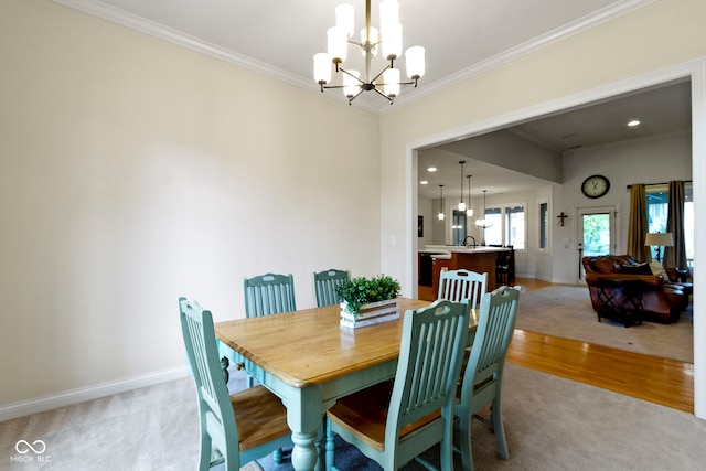 dining space with crown molding, baseboards, a notable chandelier, and light carpet