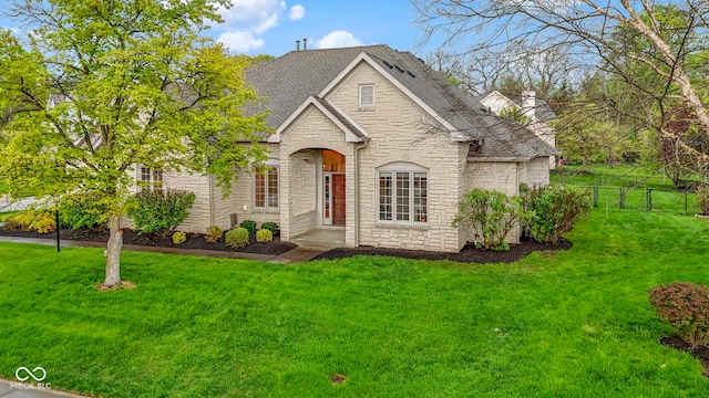 view of front of home with a front lawn, fence, and stone siding