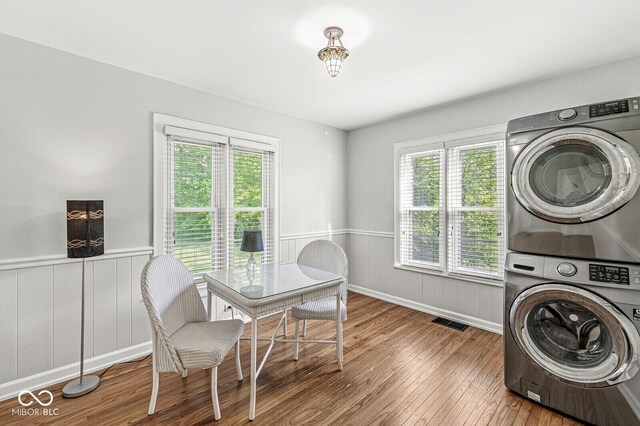 5747 Allisonville Rd, Indianapolis, IN 46220 - laundry room featuring stacked washer / dryer, hardwood / wood-style floors, wainscoting, and laundry area
