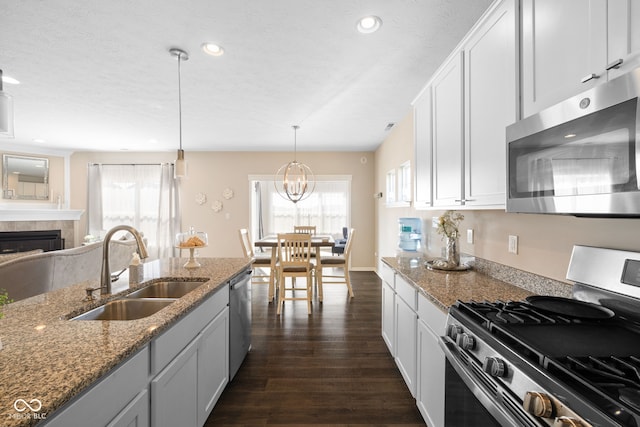 7067 Hart St, Cumberland, IN 46229 - kitchen with appliances with stainless steel finishes, a sink, dark wood finished floors, light stone counters, and a fireplace