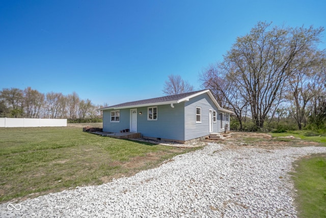 exterior space with a lawn, fence, and gravel driveway