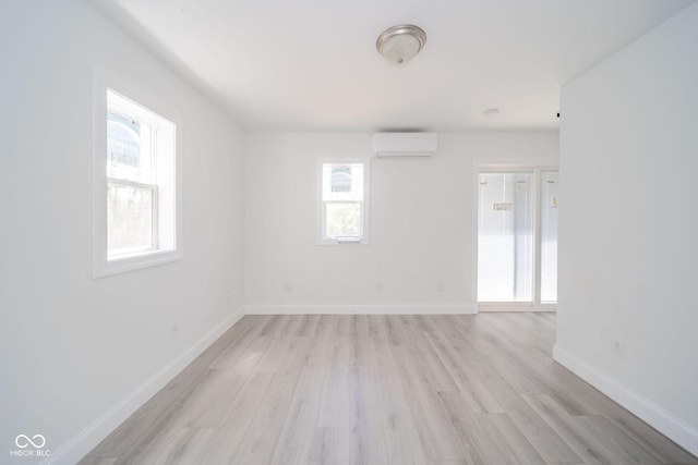 spare room with light wood-style floors, baseboards, and a wall mounted air conditioner