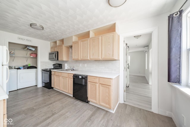kitchen with a sink, independent washer and dryer, black appliances, and light brown cabinets