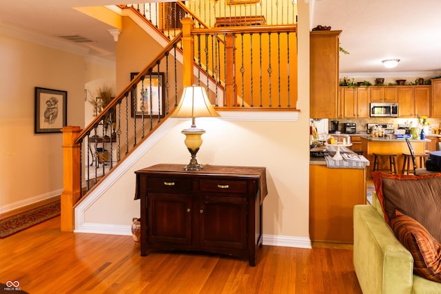 stairs featuring wood finished floors, crown molding, visible vents, and baseboards