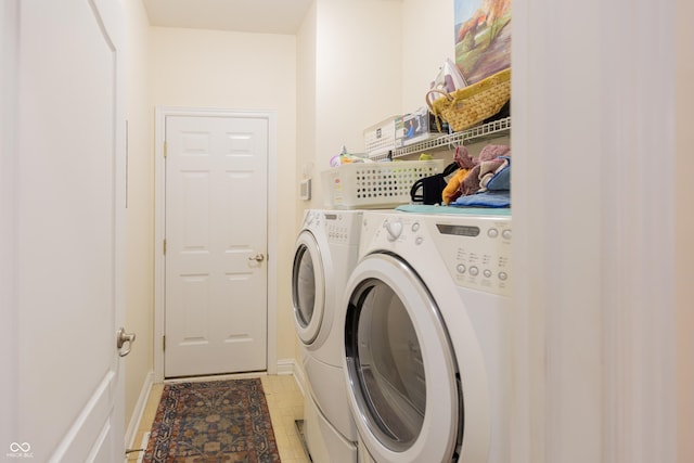 washroom with light tile patterned flooring, separate washer and dryer, laundry area, and baseboards
