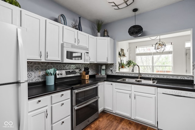 kitchen with decorative backsplash, dark countertops, white appliances, white cabinetry, and a sink