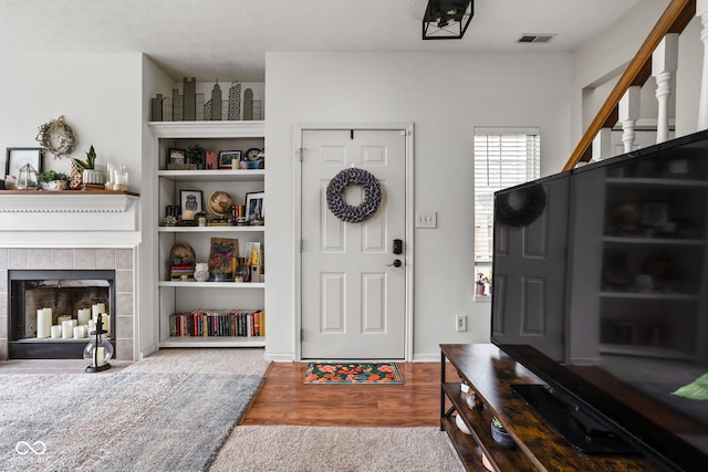 foyer entrance featuring a fireplace, wood finished floors, and visible vents