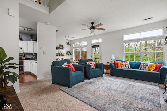 carpeted living area featuring a ceiling fan and visible vents