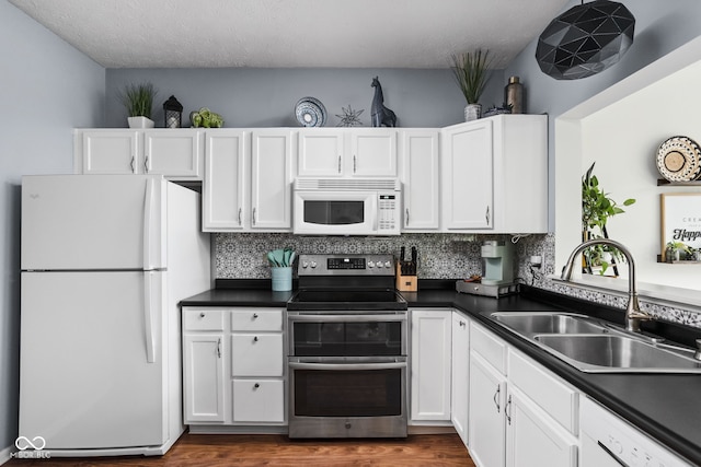 kitchen with white appliances, white cabinets, and a sink