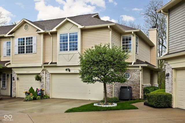 view of property featuring brick siding, central AC unit, a shingled roof, an attached garage, and driveway