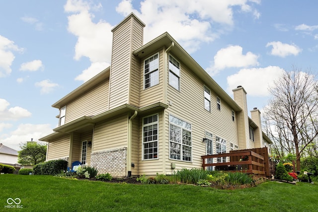 view of side of property with a wooden deck, a yard, and a chimney