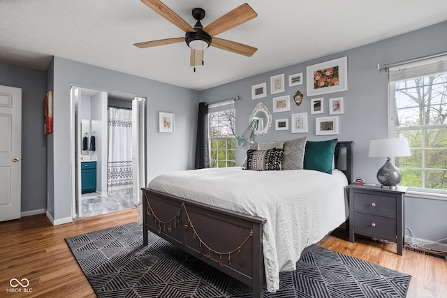bedroom with connected bathroom, baseboards, ceiling fan, and light wood finished floors
