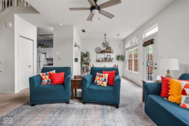 carpeted living area featuring baseboards, ceiling fan, and visible vents