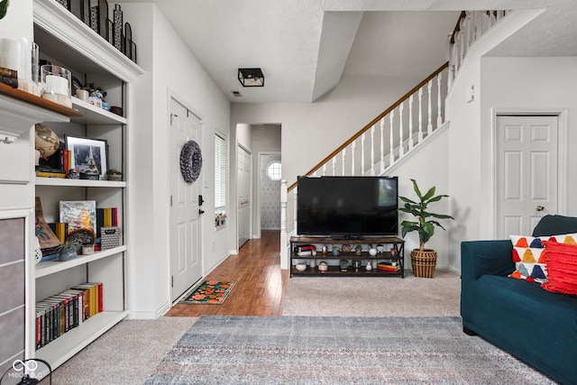 living room featuring baseboards, carpet, stairs, and wood finished floors