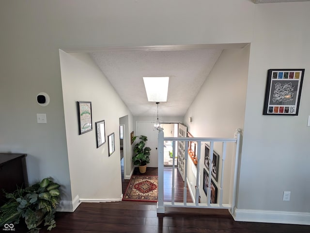 hallway with baseboards, a skylight, and wood finished floors