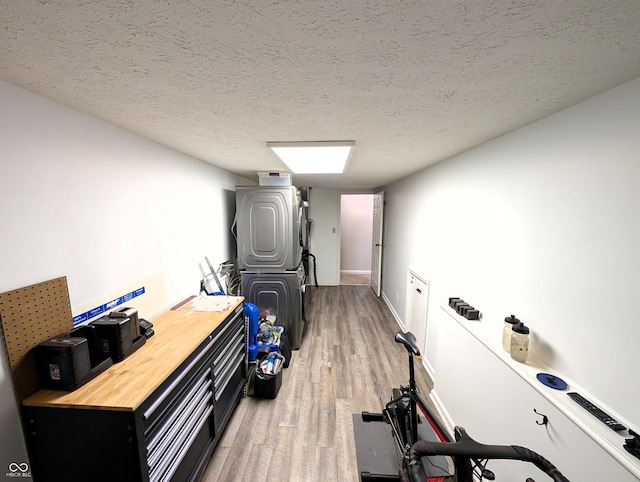 exercise area with baseboards, a textured ceiling, and light wood finished floors