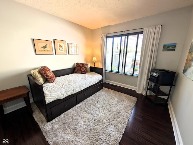 bedroom featuring baseboards, a textured ceiling, dark wood-style flooring, and visible vents