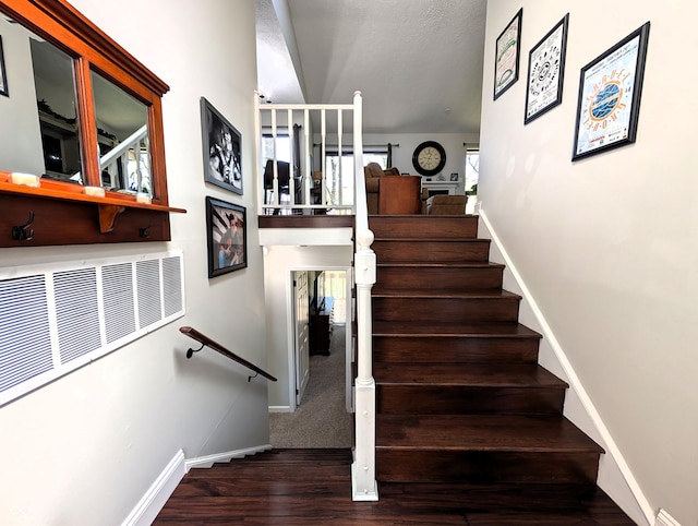 staircase with baseboards, wood finished floors, and visible vents