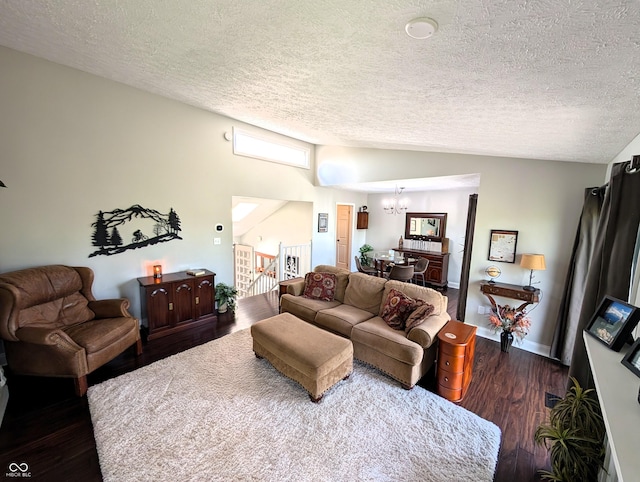living area with lofted ceiling, dark wood finished floors, a textured ceiling, and a notable chandelier