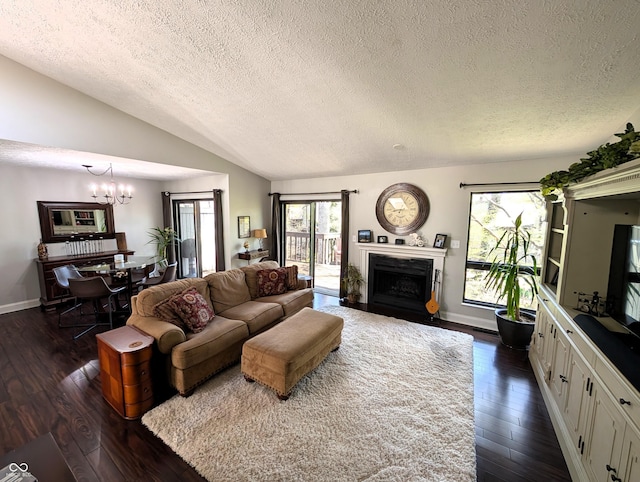 living room with an inviting chandelier, a fireplace with flush hearth, dark wood finished floors, and a textured ceiling
