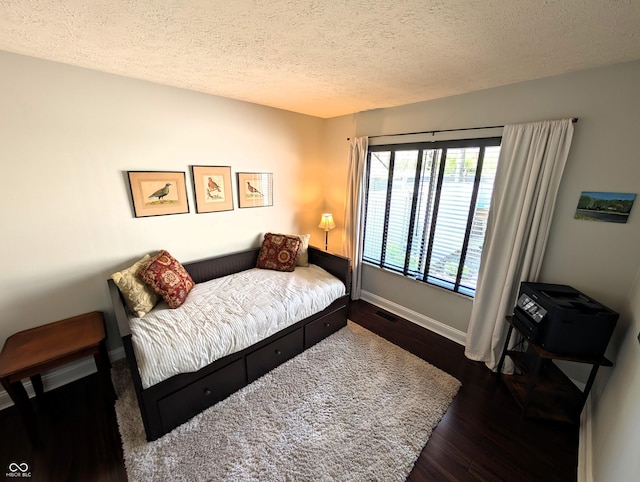 bedroom with a textured ceiling, visible vents, baseboards, and dark wood-type flooring